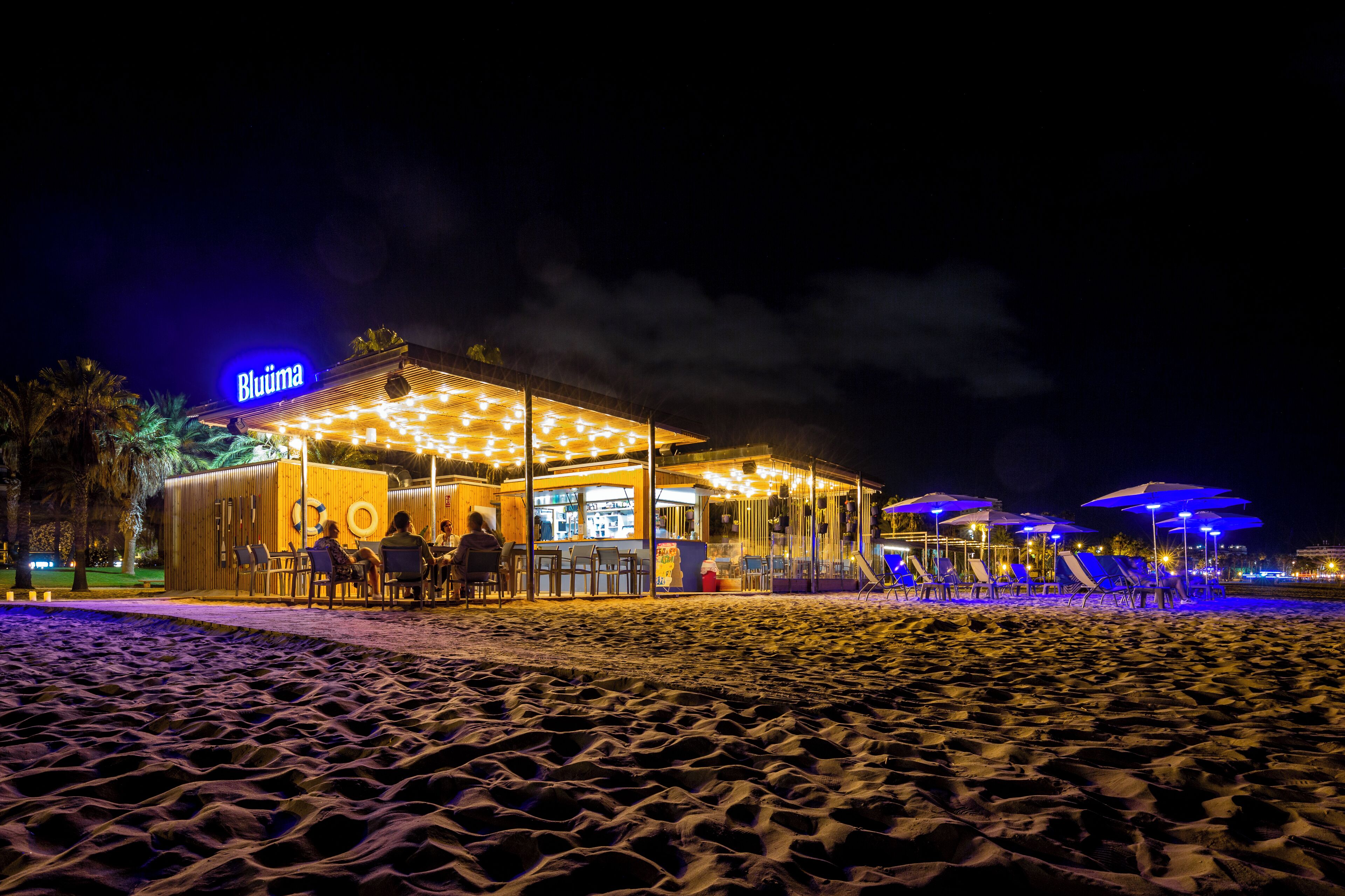 A beachside restaurant with outdoor seating and umbrellas.