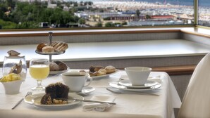 Una mesa servida con alimentos para el desayuno y vistas a una playa y una noria.