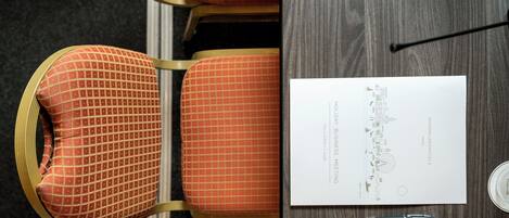 A conference table with a business card, pens, and a chair with a checkered pattern.