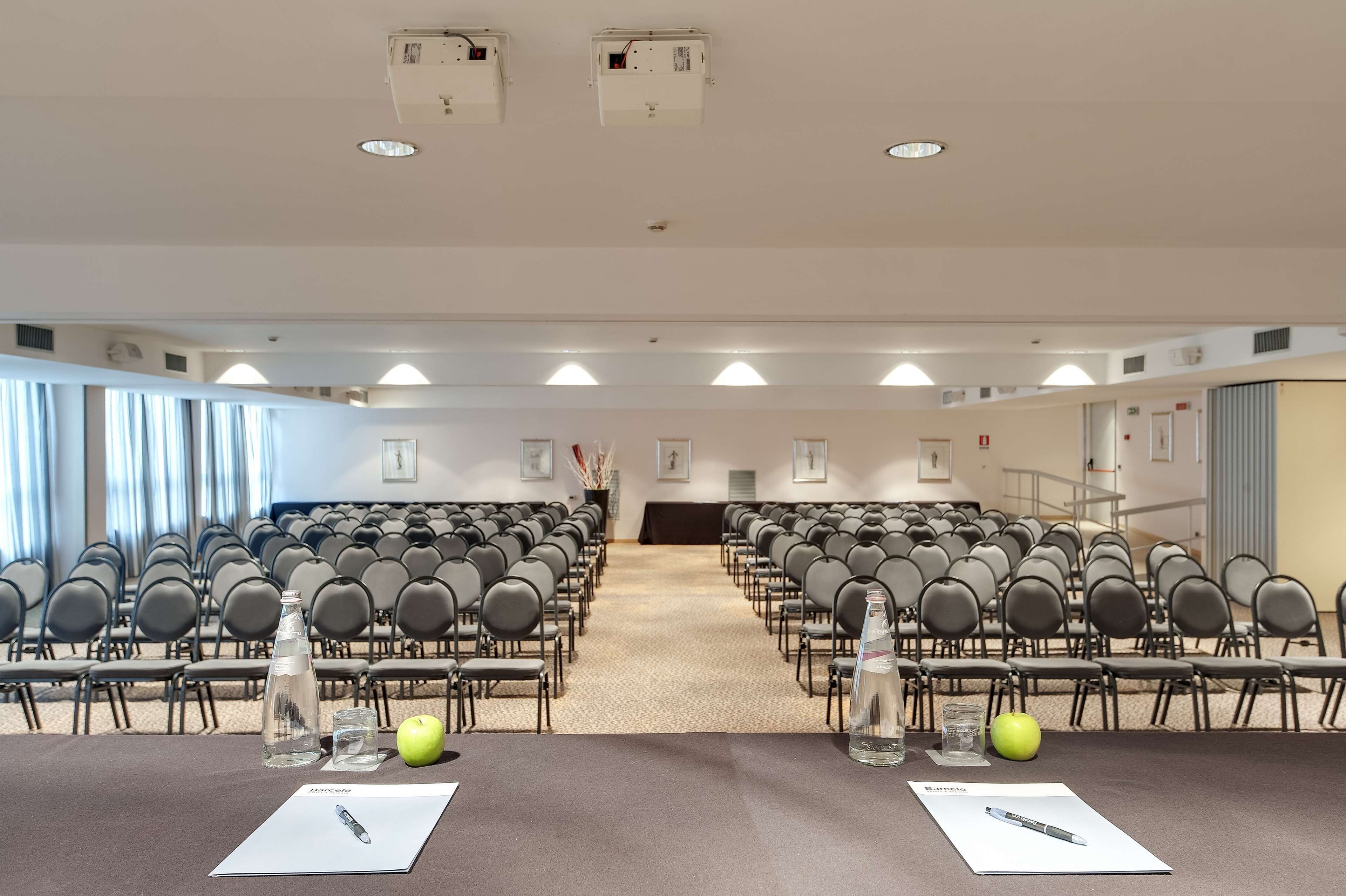 Une salle de conférence avec des rangées de chaises, un pupitre et un sol recouvert de moquette.