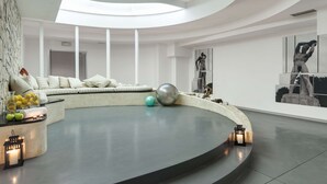A modern interior with a curved seating area, a central round table, and a skylight. - Occidental Aran Park (Rome)