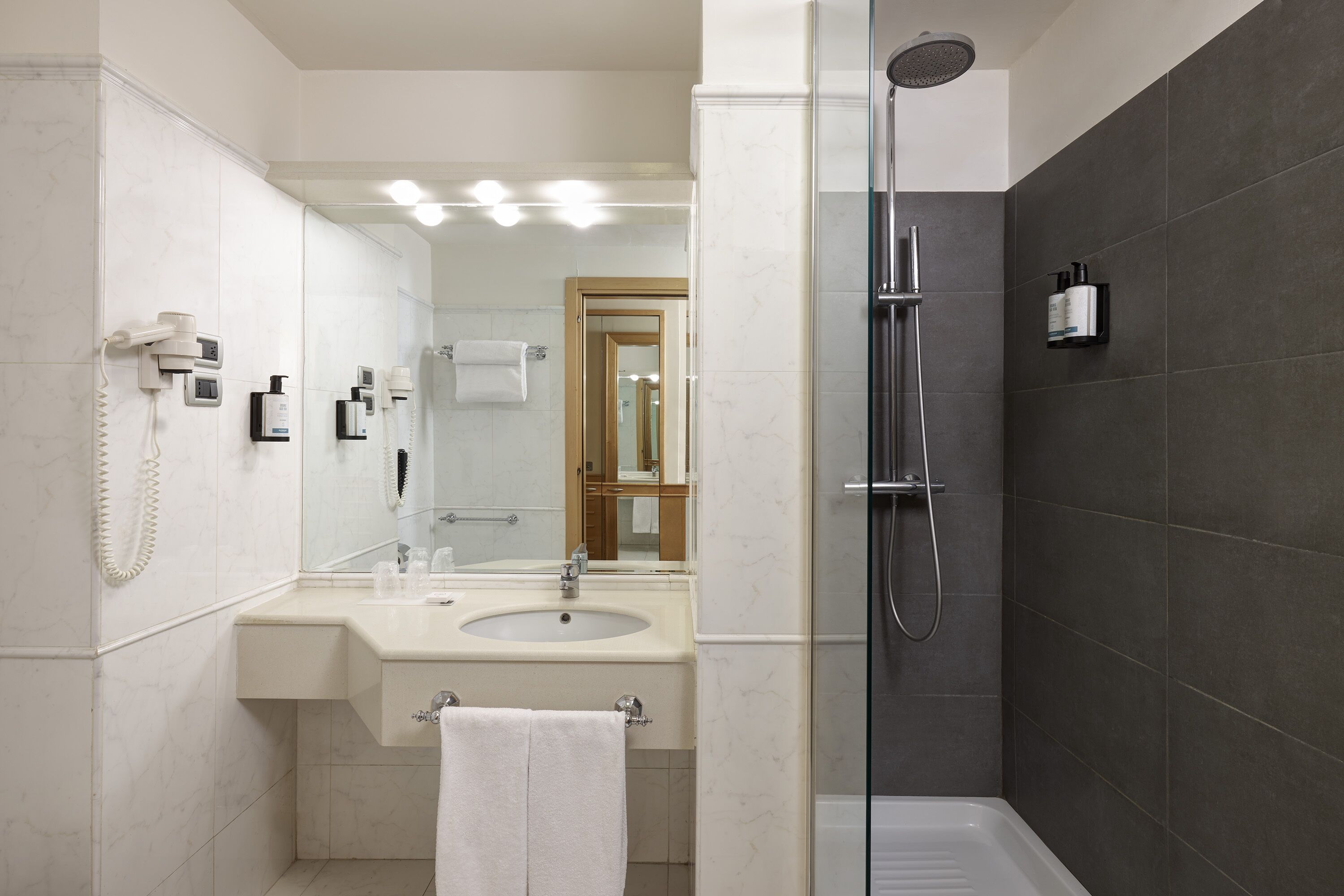 Un baño moderno con ducha de vidrio, lavabo con espejo y barra para toallas.