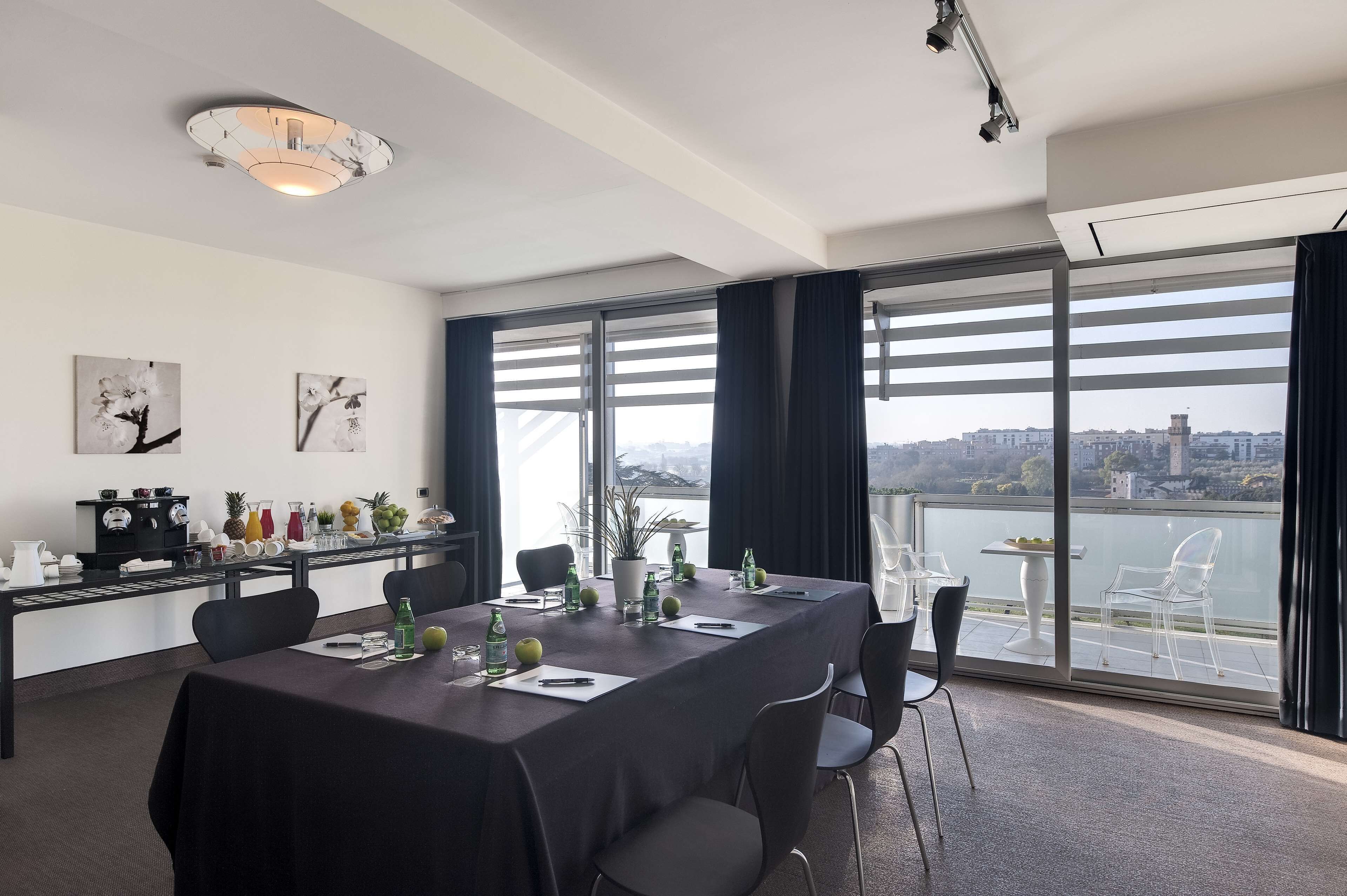 A conference room with a long table, chairs, a buffet setup, and large windows with a city view.