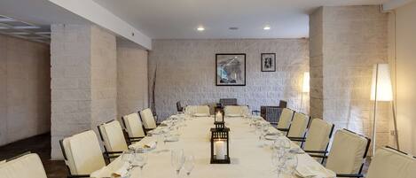 A conference room with a long table set for a meeting, surrounded by chairs, with a candle in a lantern at the center.