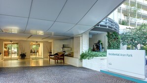 A spacious lobby with a tiled floor, a wooden bench, and a sign reading "Occidental Aran Park." - Occidental Aran Park (Rome)