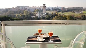 A balcony table with breakfast items and a view of a historic tower and buildings. - Occidental Aran Park (Rome)
