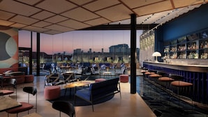 A modern bar area with seating, a bar counter, and a view of the cityscape. - Le Méridien Visconti Rome (Rome)