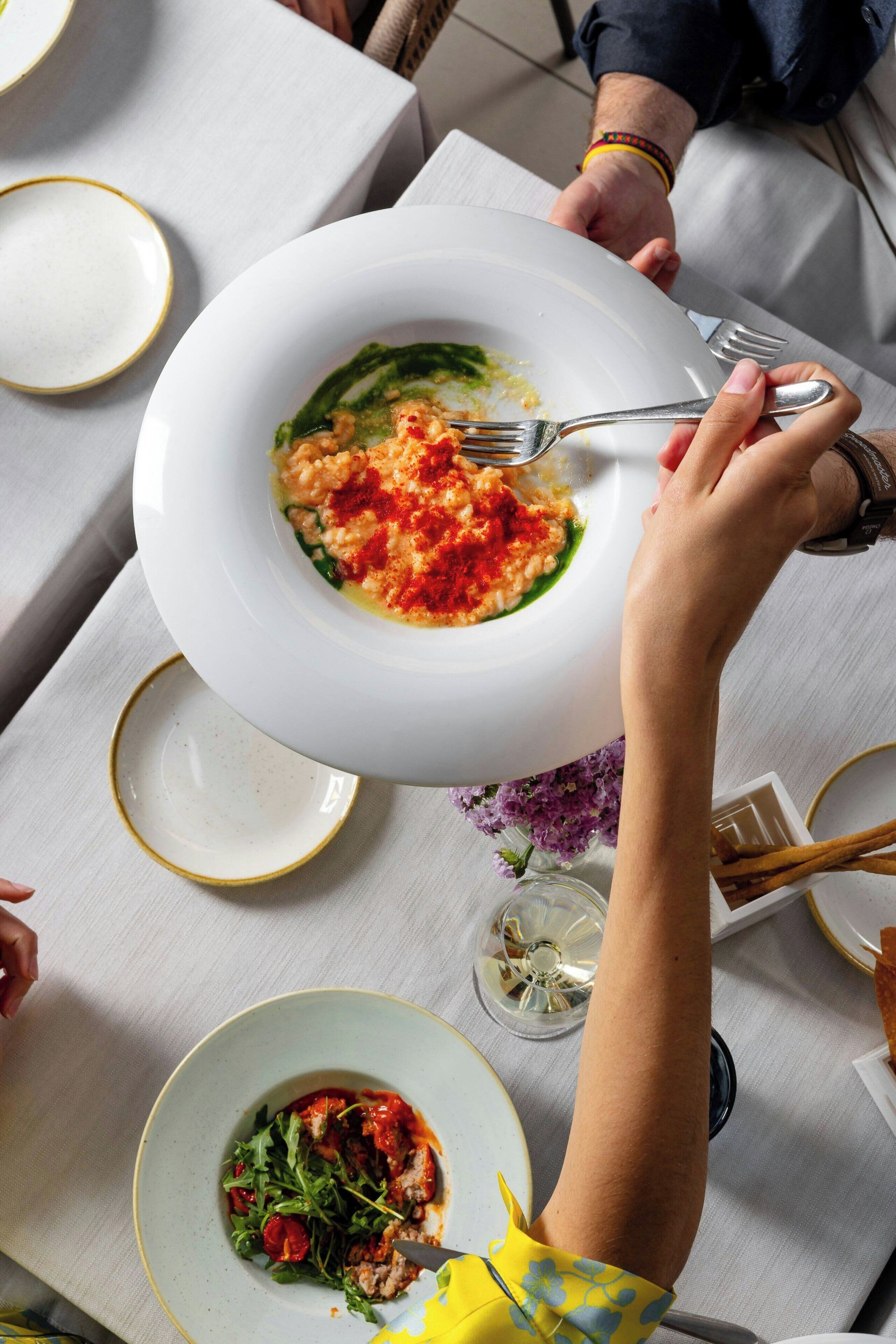 A dining table with a plate of food, a fork, and a glass of water.