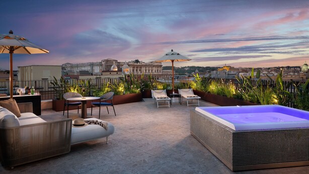 A rooftop terrace with outdoor seating, a hot tub, and a view of historic buildings. - Le Méridien Visconti Rome (Rome)