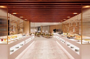 A modern hotel lobby with a long reception desk, seating area, and a buffet with various food items.