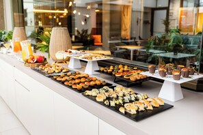 Un bufé con diversos alimentos y un bol de fruta.