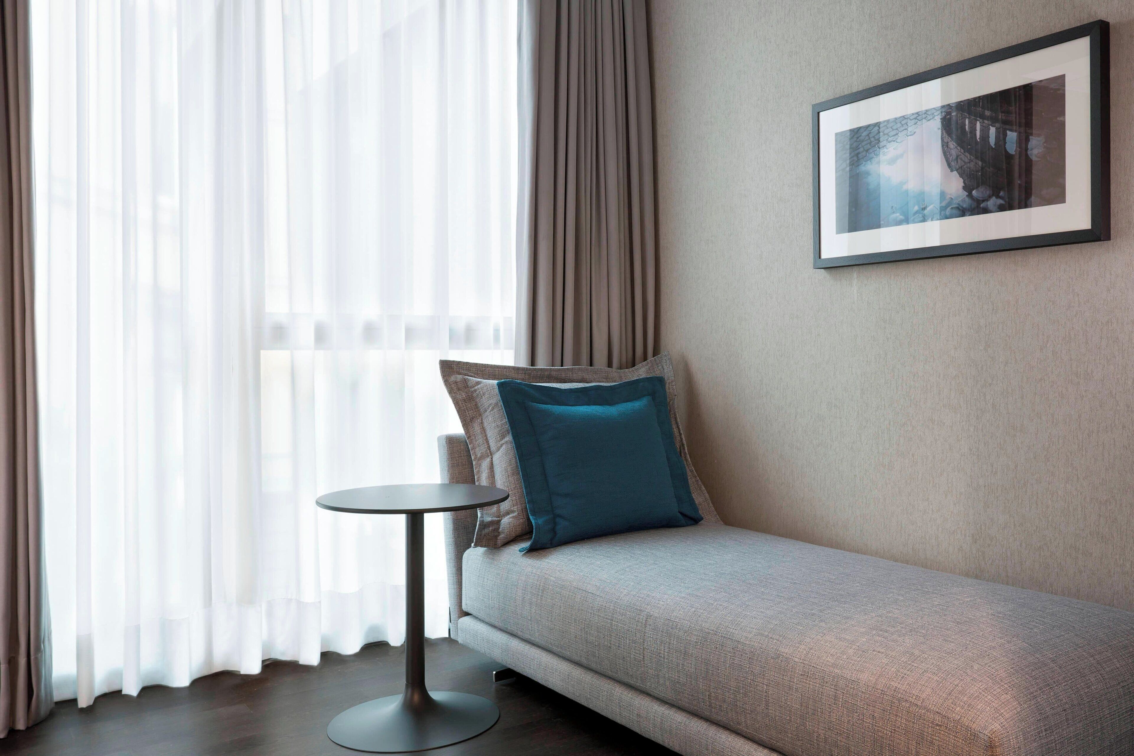 A modern room with a sofa, a small round table, and a framed picture on the wall.