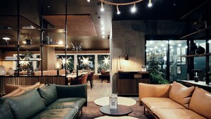 A modern lounge area with leather sofas, round tables, and pendant lighting. - Bergstadens Hotel & SPA (Roros)