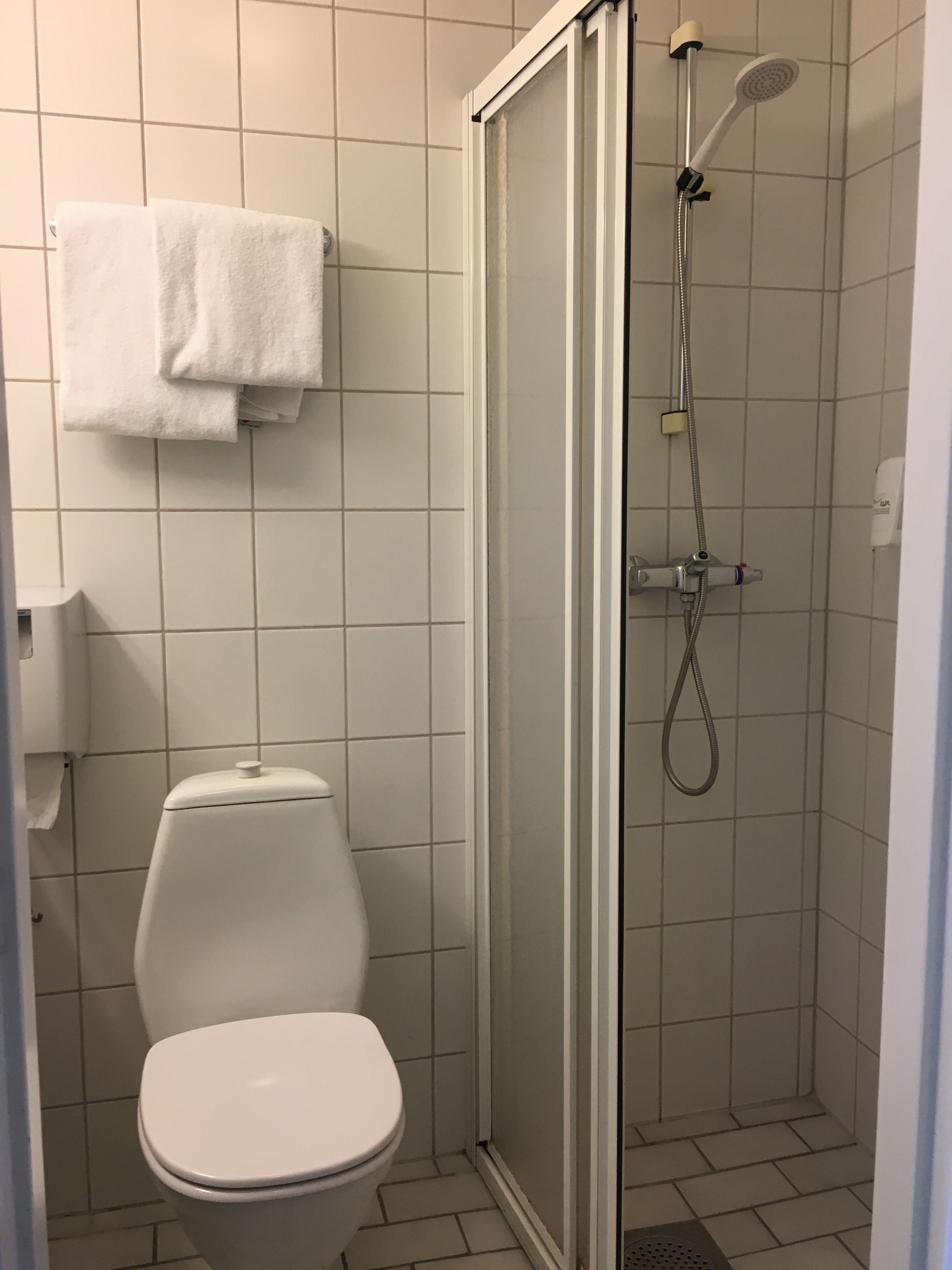 A bathroom with a toilet, a shower enclosure, and a towel rack.