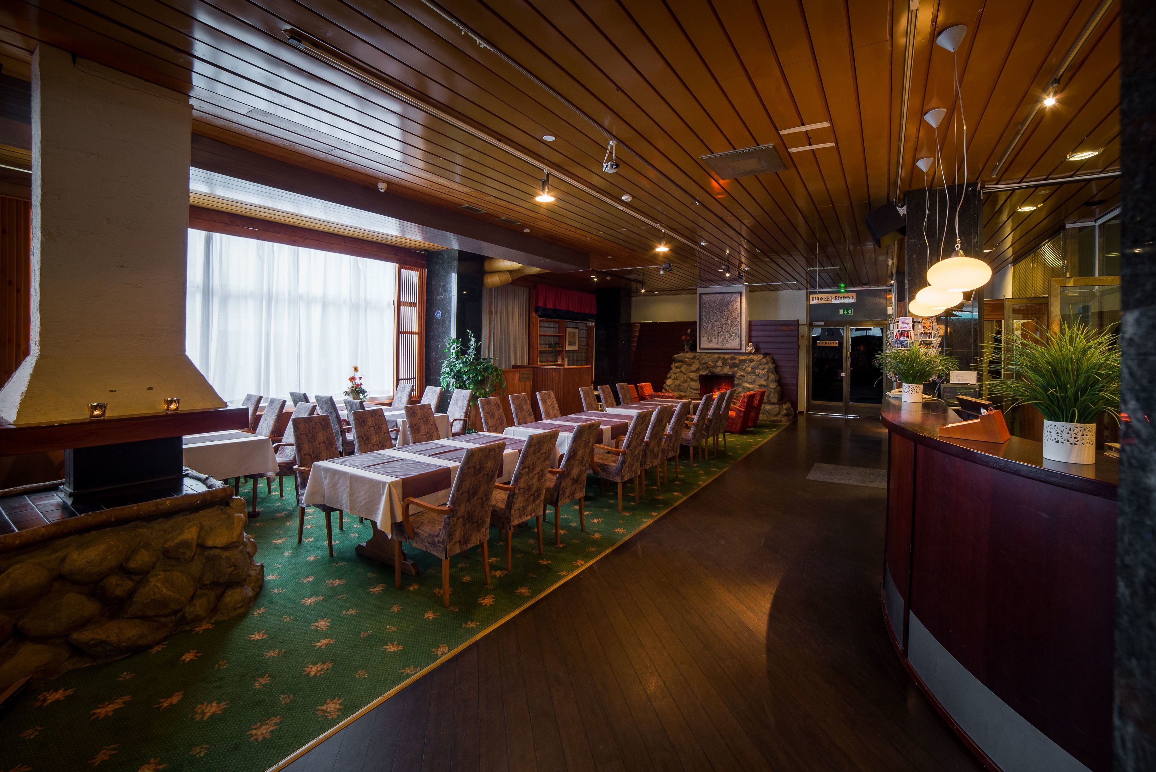 Un restaurante con techo de madera, mesas, sillas y chimenea de piedra.