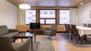 Un salon moderne comprenant un canapé, un fauteuil, un téléviseur et une table à manger.