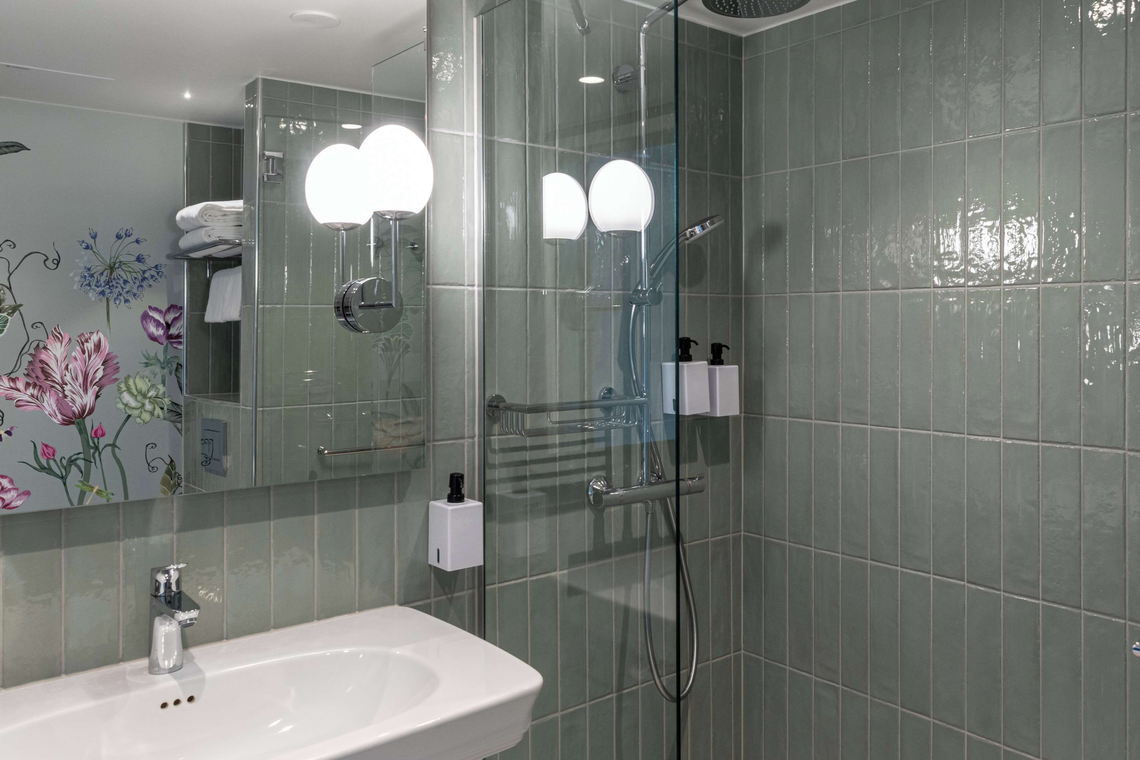 Une salle de bain avec un lavabo, un miroir et une douche.