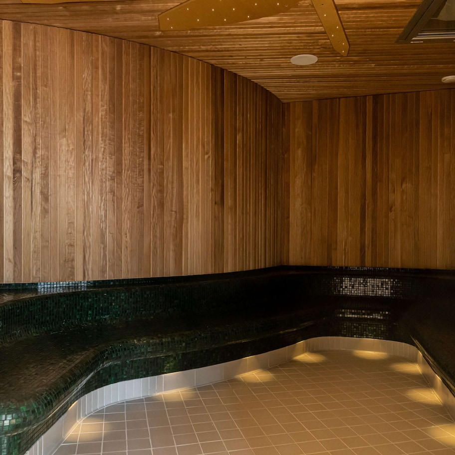 A wooden sauna with a curved bench and tiled floor.