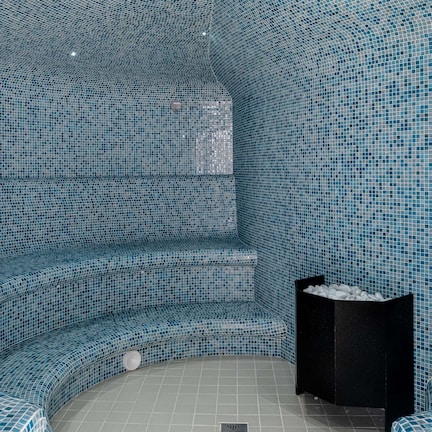A spa area with a curved seating arrangement and a black trash bin.