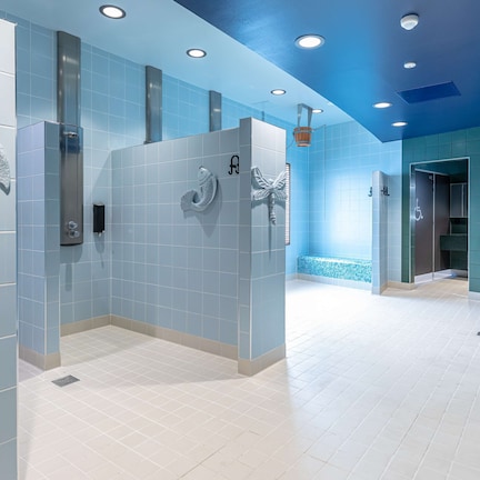 A modern bathroom with blue and white tiles, a shower area, and a wall-mounted towel rack.