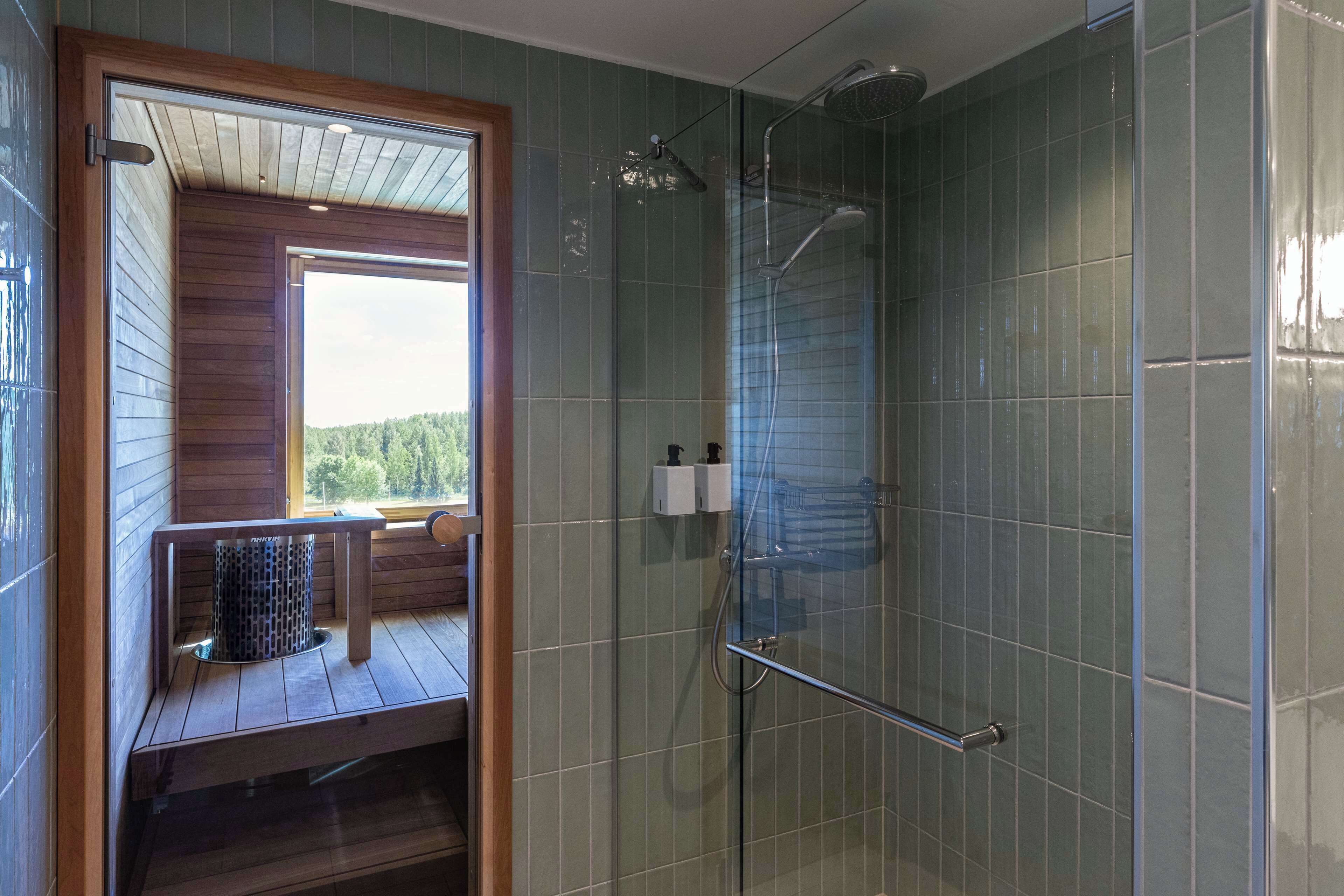 A glass-enclosed shower with a metal handle and a handheld showerhead.