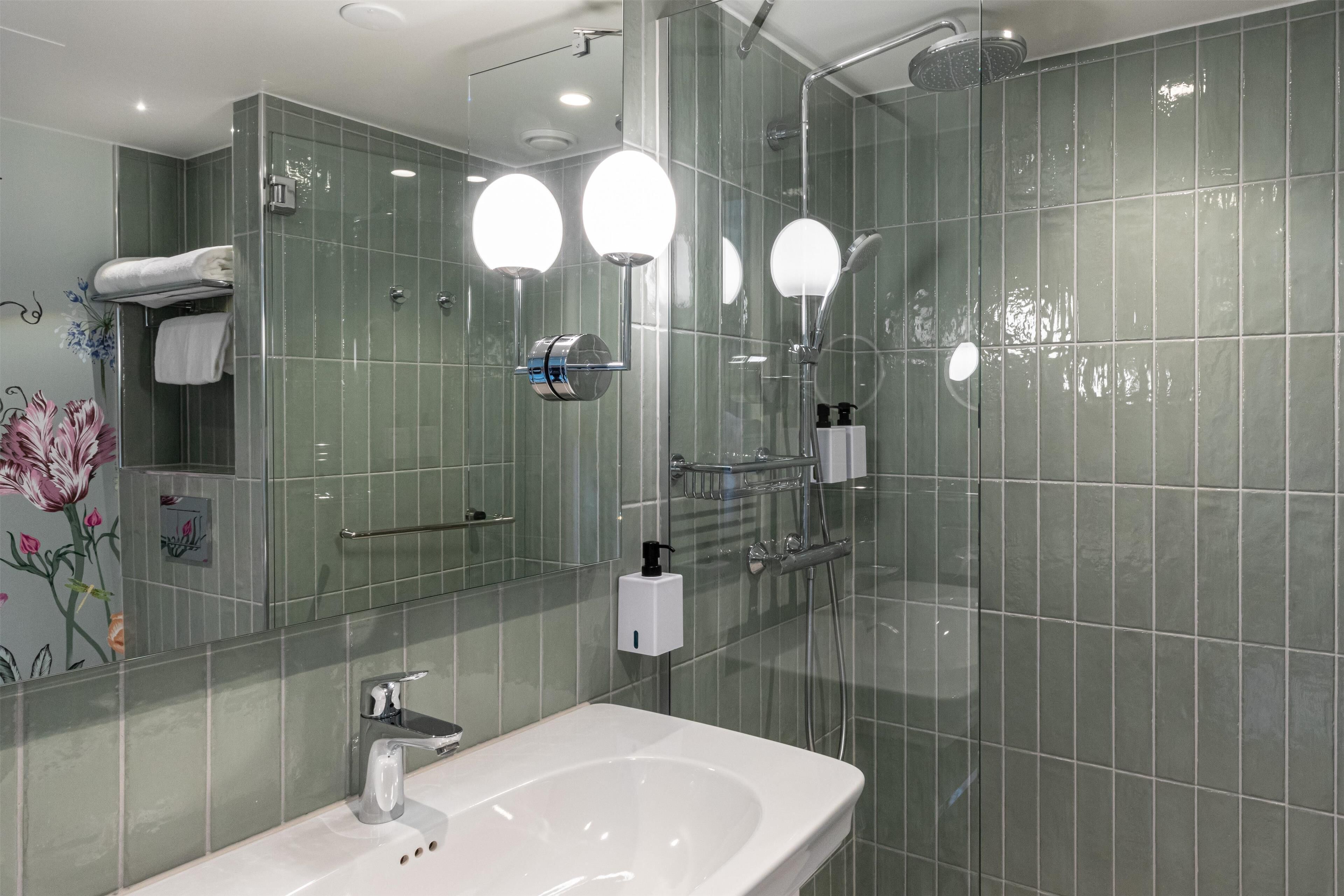 Une salle de bain moderne avec une douche à parois de verre, un lavabo blanc et un miroir agrémenté de trois lampes rondes.