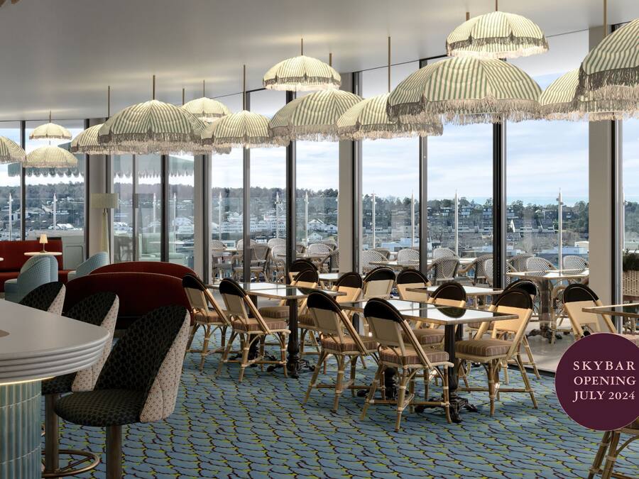 Un ristorante moderno con soffitti alti, ampie finestre e vista sulla città.
