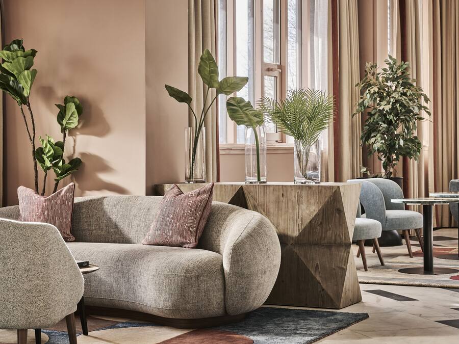 A modern living room with a sofa, armchairs, a coffee table, and decorative plants.