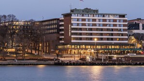 Un hotel de varios pisos con techo plano, ventanas amplias y una bandera en la parte superior.