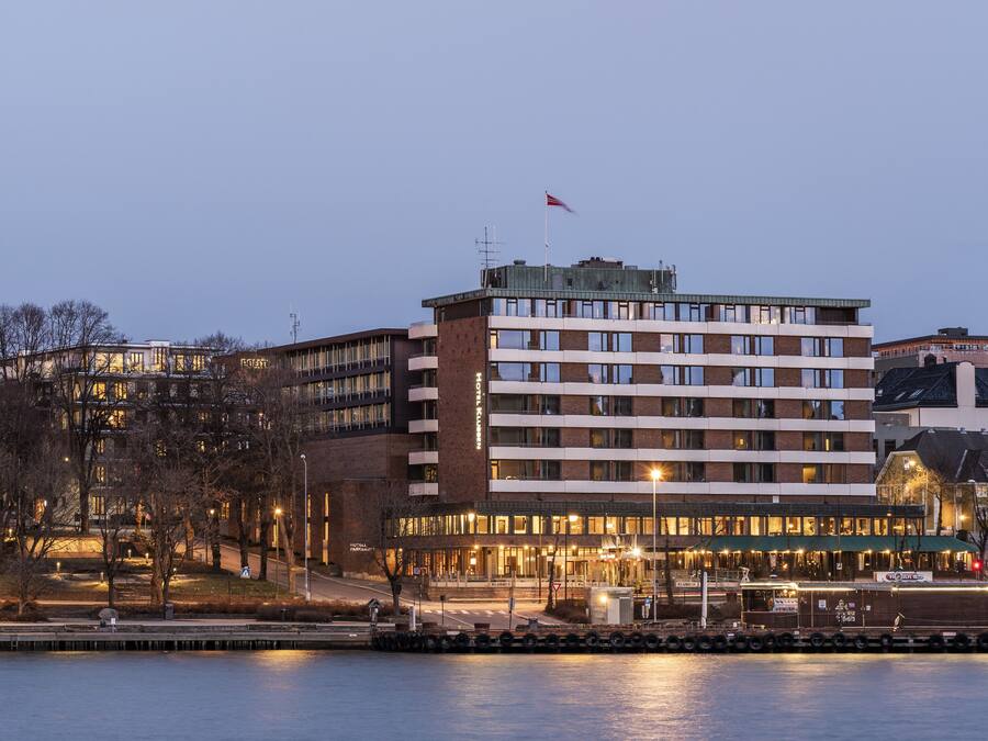 A multi-story hotel with a flat roof, large windows, and a flag on top.
