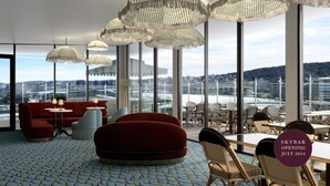 Un salón amplio con vistas a la ciudad, ventanas grandes y mobiliario moderno.