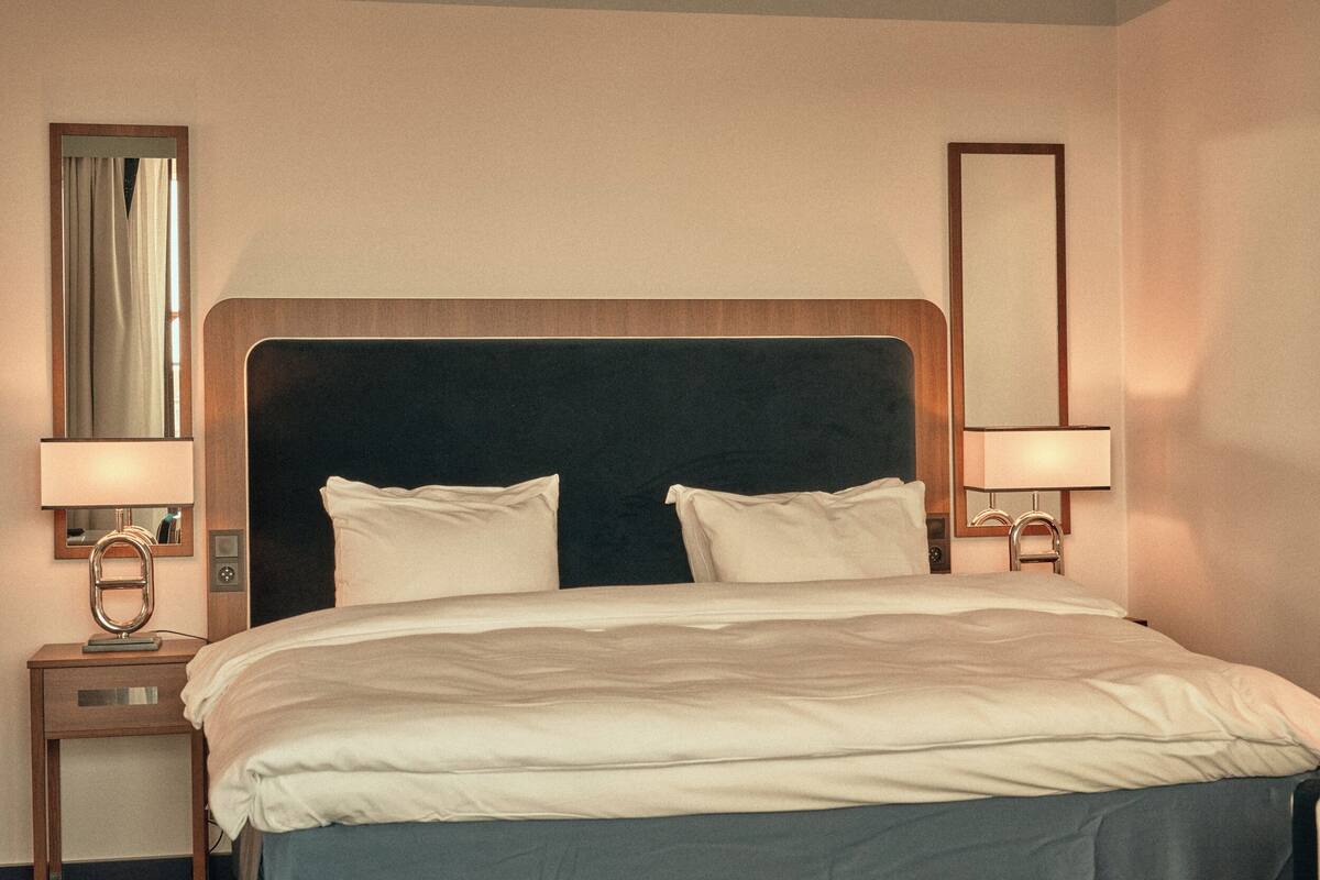 A hotel room with a large bed, two bedside tables, and a mirror on each wall.