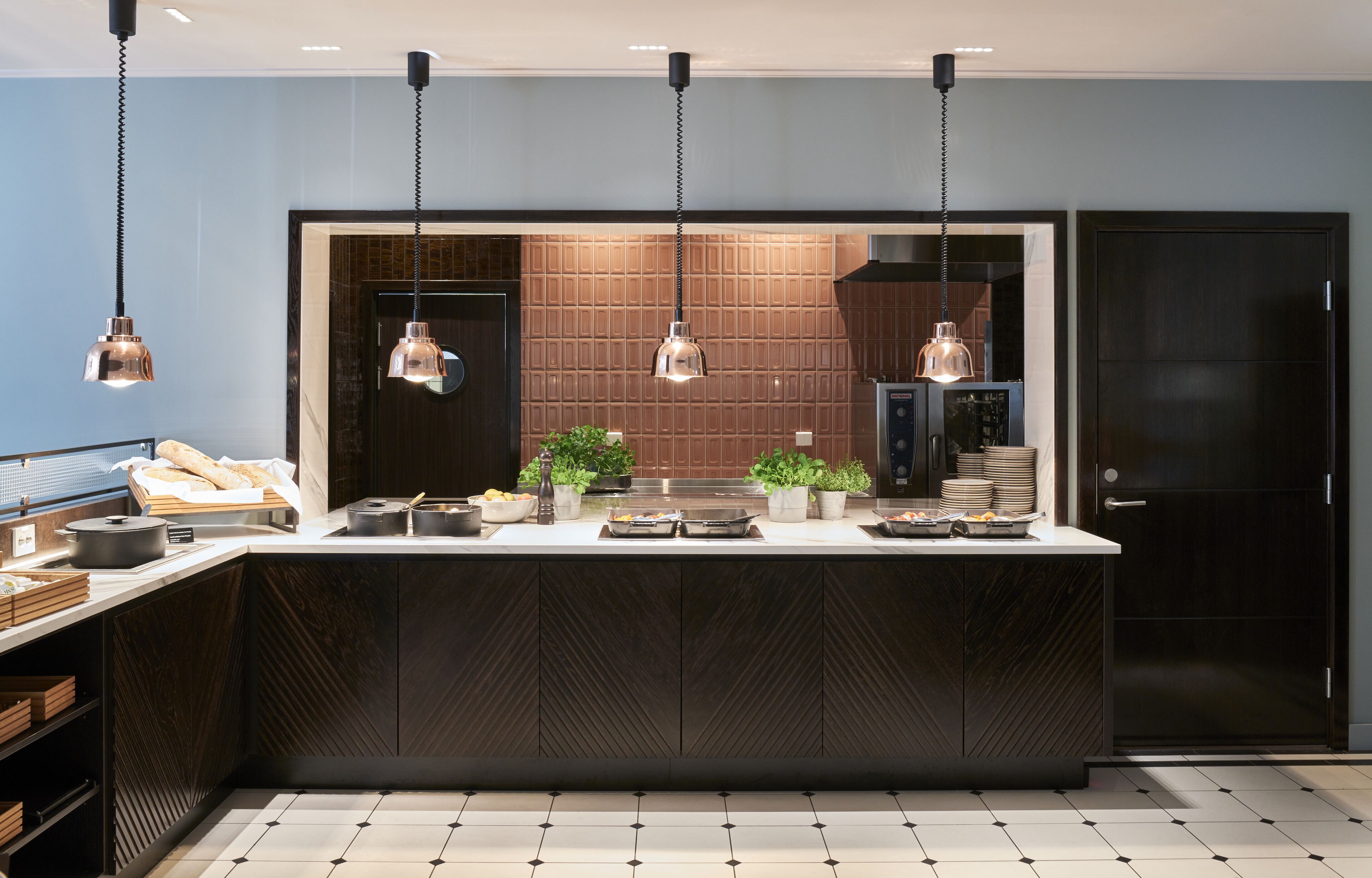 A modern kitchen with a central island, pendant lighting, and a dark wooden cabinet.