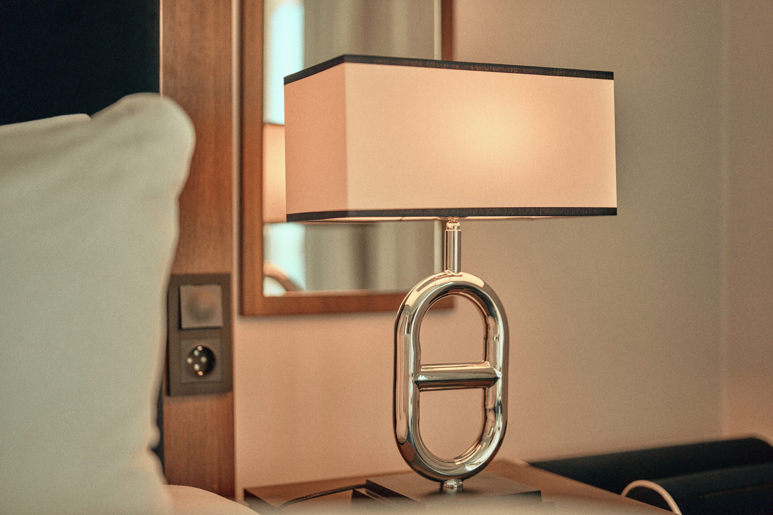 A modern lamp with a rectangular shade on a bedside table.