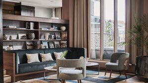 Una sala de estar moderna con un sofá verde oscuro, dos sillones grises, una mesa de centro y una estantería llena de libros y objetos decorativos.