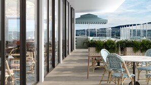 Un área de comedor exterior moderna con mobiliario de mimbre y vistas a la ciudad.