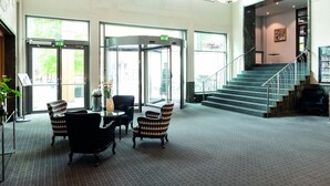A lobby with a revolving door, a staircase, and seating area. - Elite Stadshotellet Växjö (Växjö)