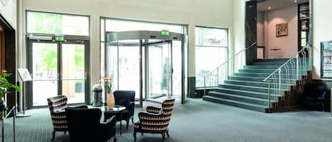 A lobby with a revolving door, a staircase, and seating area.