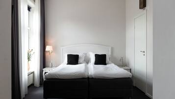 A double bed with black and white bedding, a bedside table with a lamp, and a wardrobe.