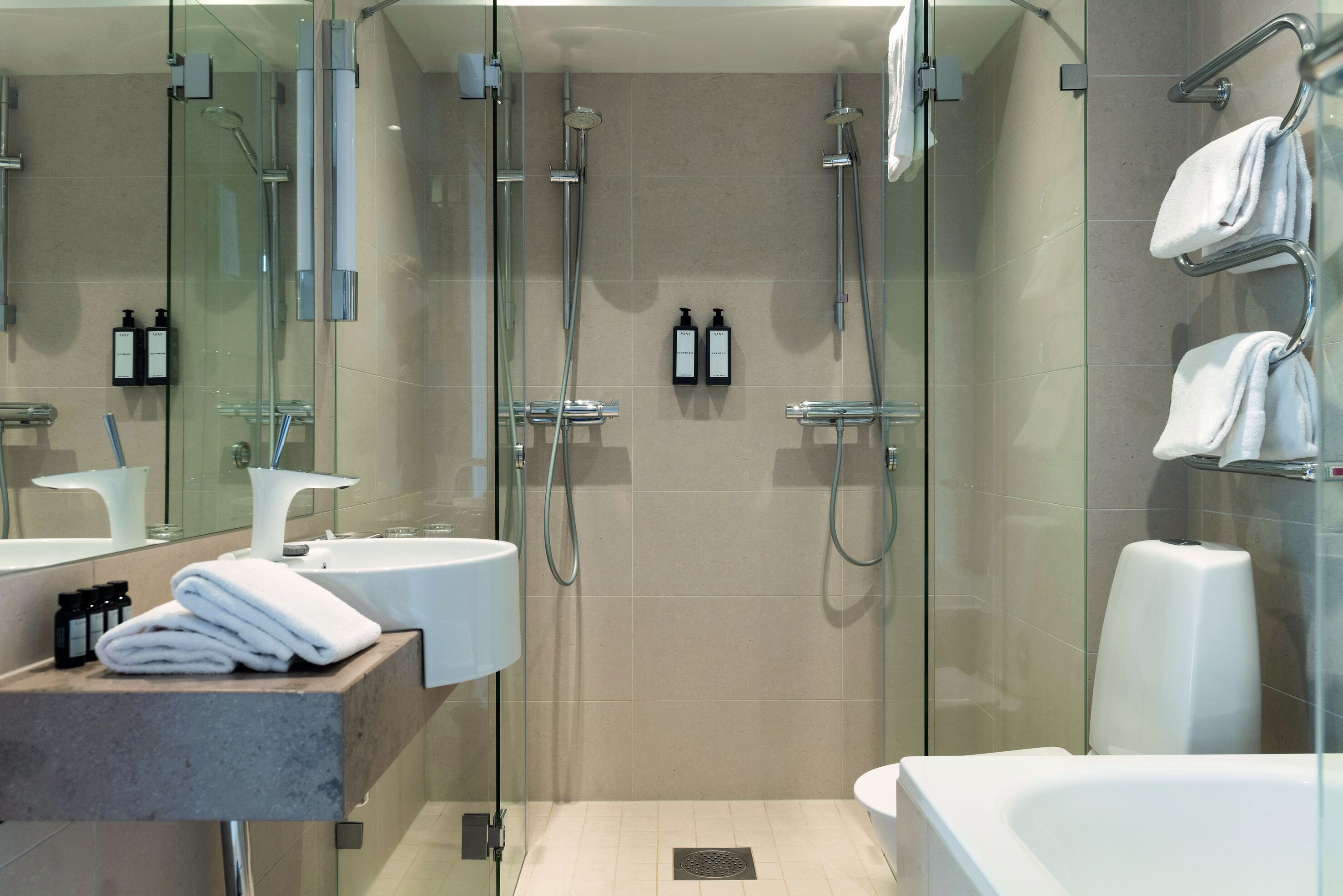 Un baño moderno con ducha de vidrio, lavamanos blanco y bañera.