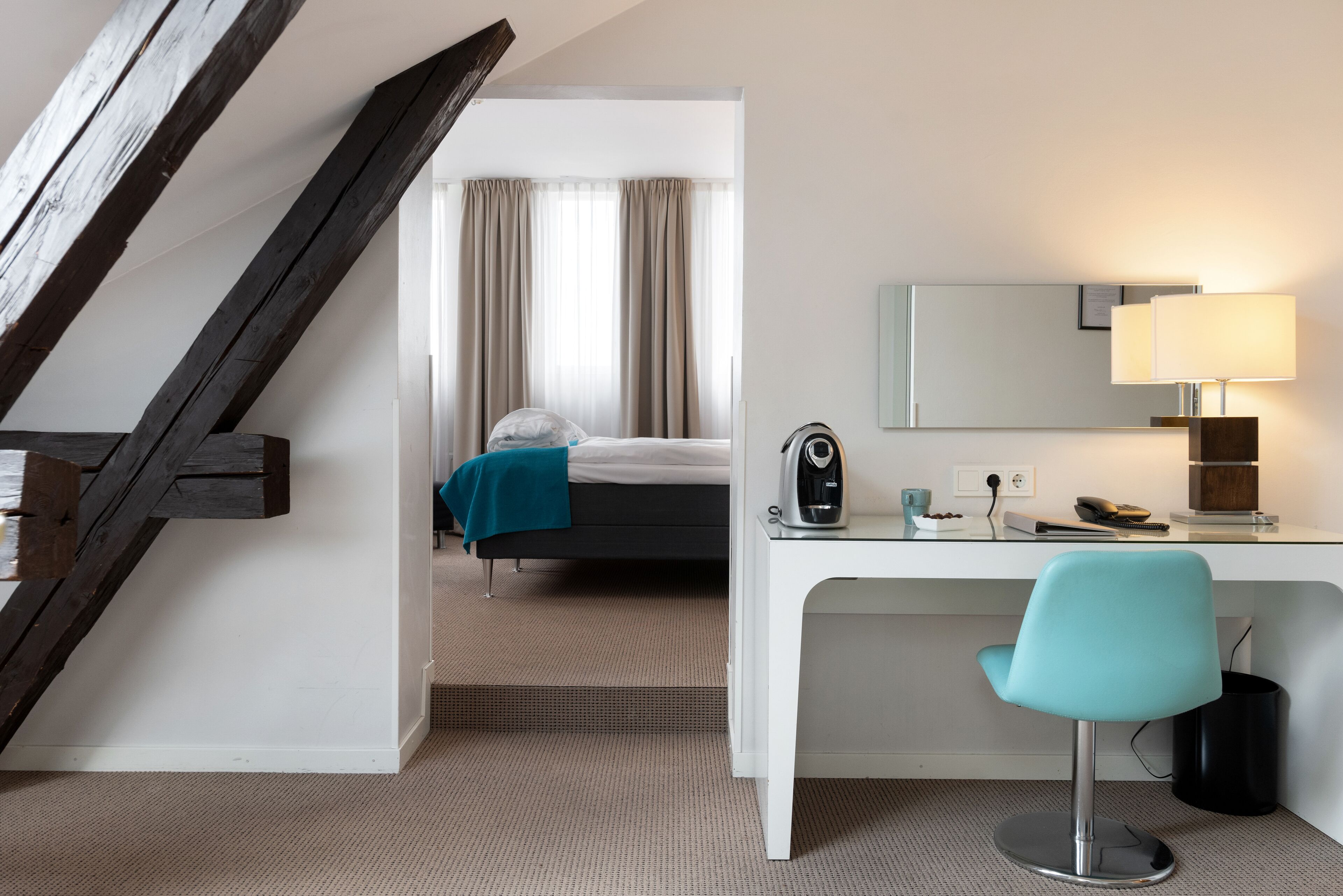 Una habitación de hotel con escritorio, silla, cama y una escalera.