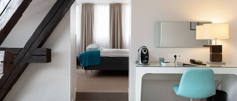 Una habitación de hotel con escritorio, silla, cama y una escalera.