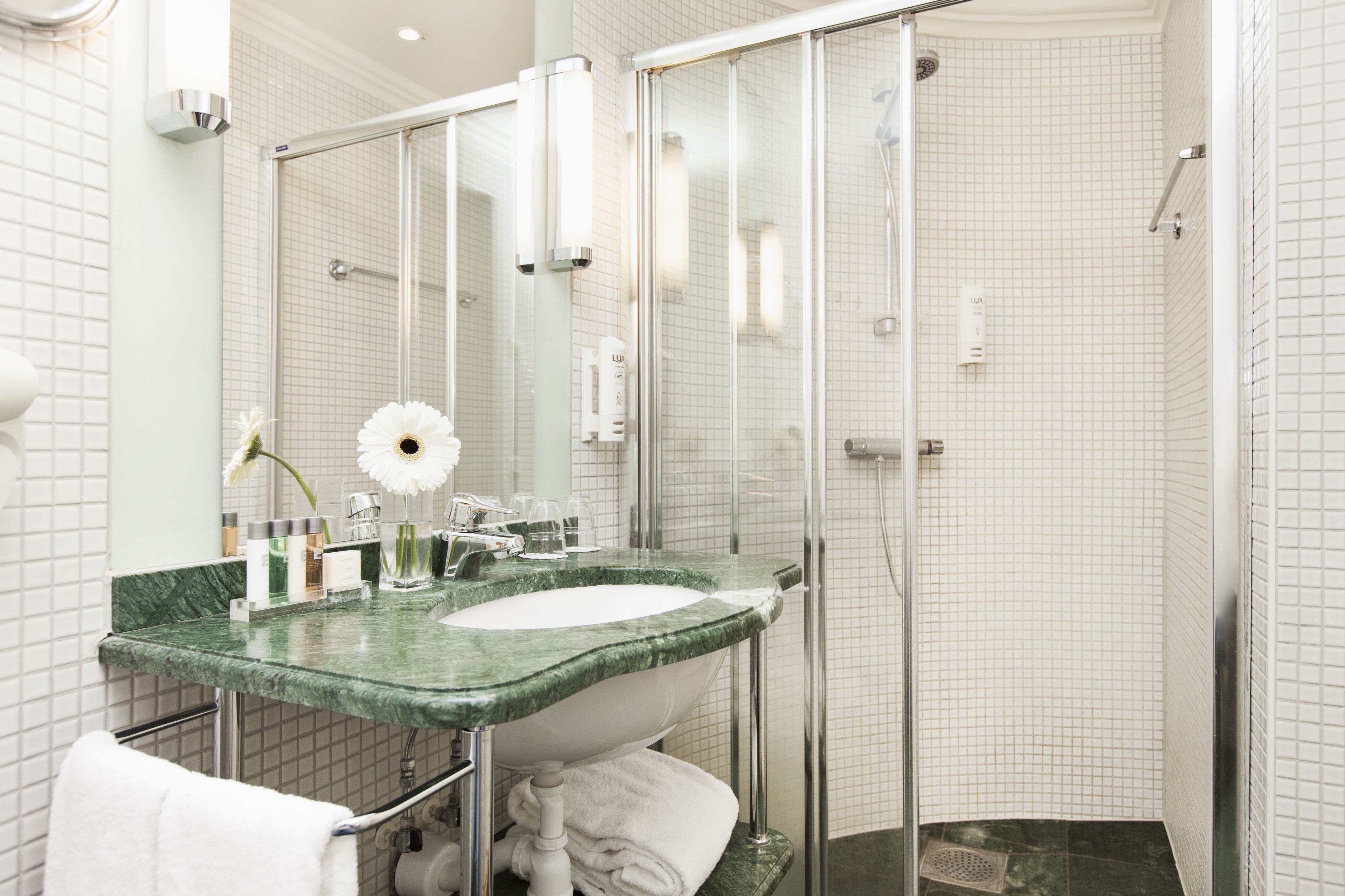 A modern bathroom with a glass-enclosed shower, a marble sink, and a large mirror.
