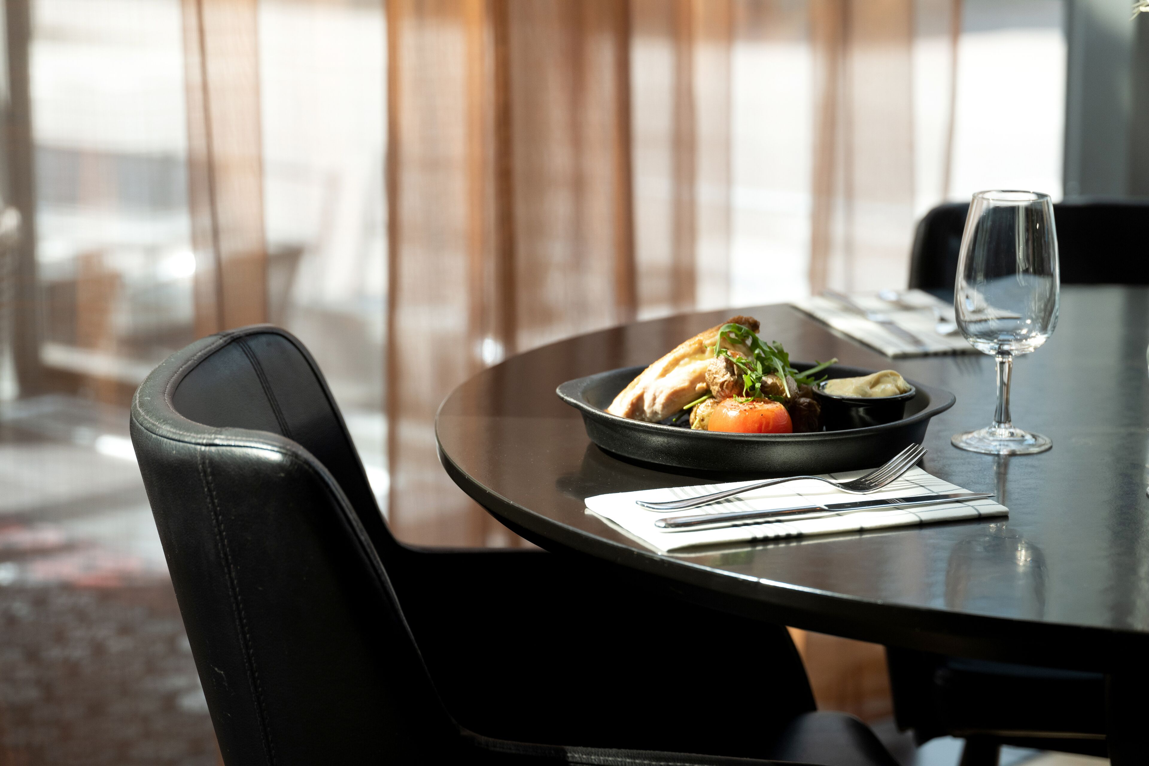 Une table à manger avec un bol de nourriture, un verre à vin et des couverts.