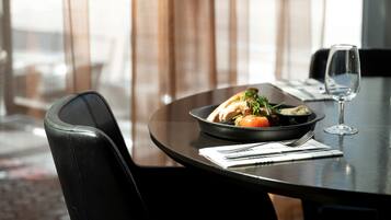 A dining table with a bowl of food, a wine glass, and cutlery.