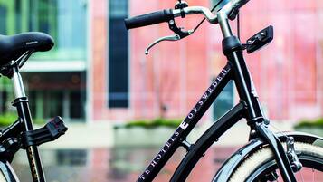 A bicycle parked in front of a building with a reflective glass facade.