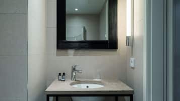 A bathroom with a sink, mirror, and two bottles on the counter.