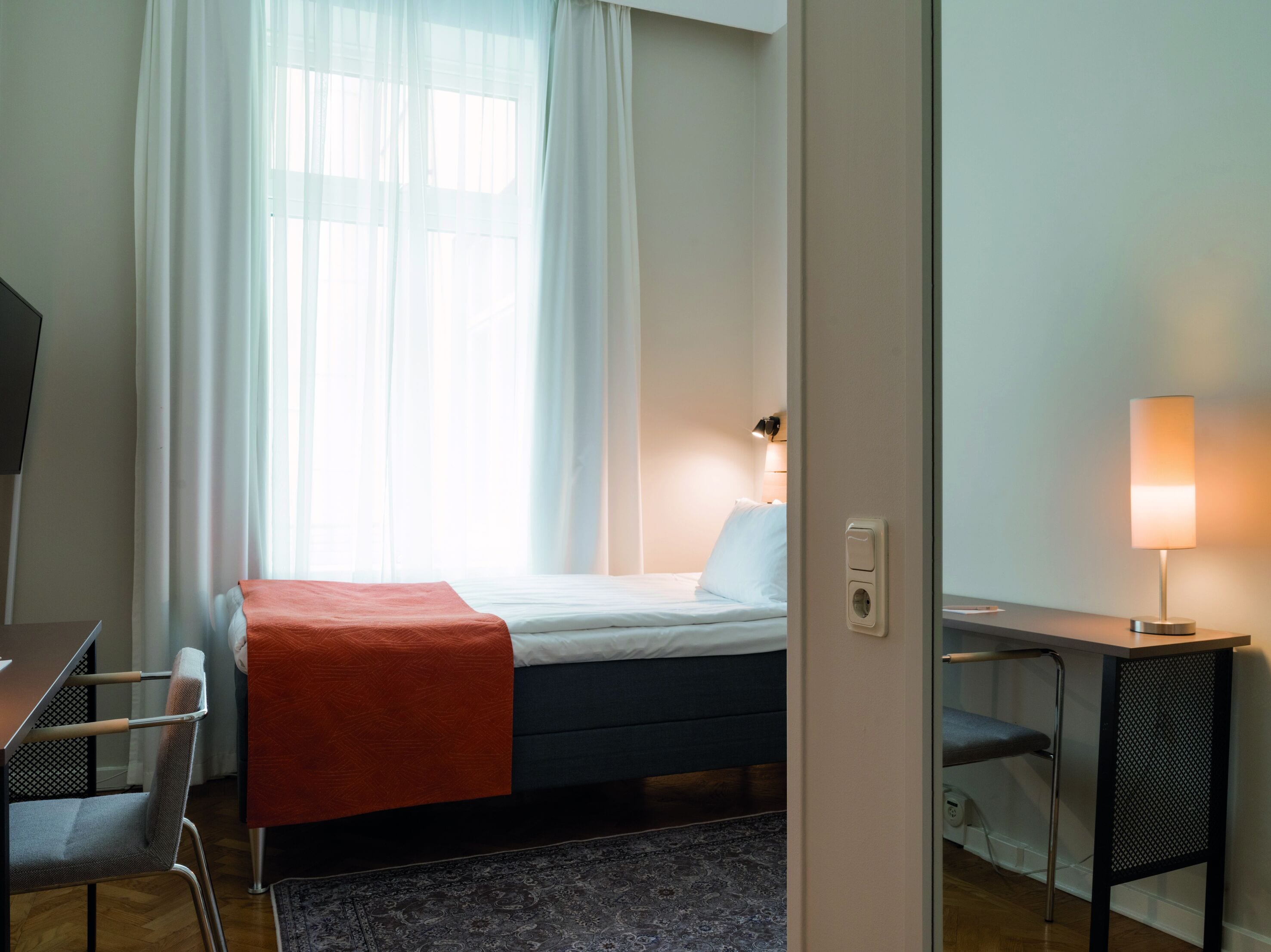 A hotel room with a bed, a desk, and a chair.