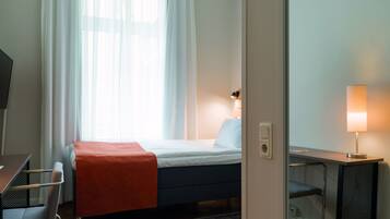 A hotel room with a bed, a desk, and a chair.