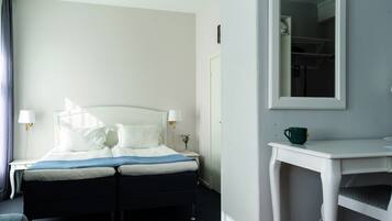 Une chambre d’hôtel avec un lit, une table de chevet, une lampe et un miroir au mur.